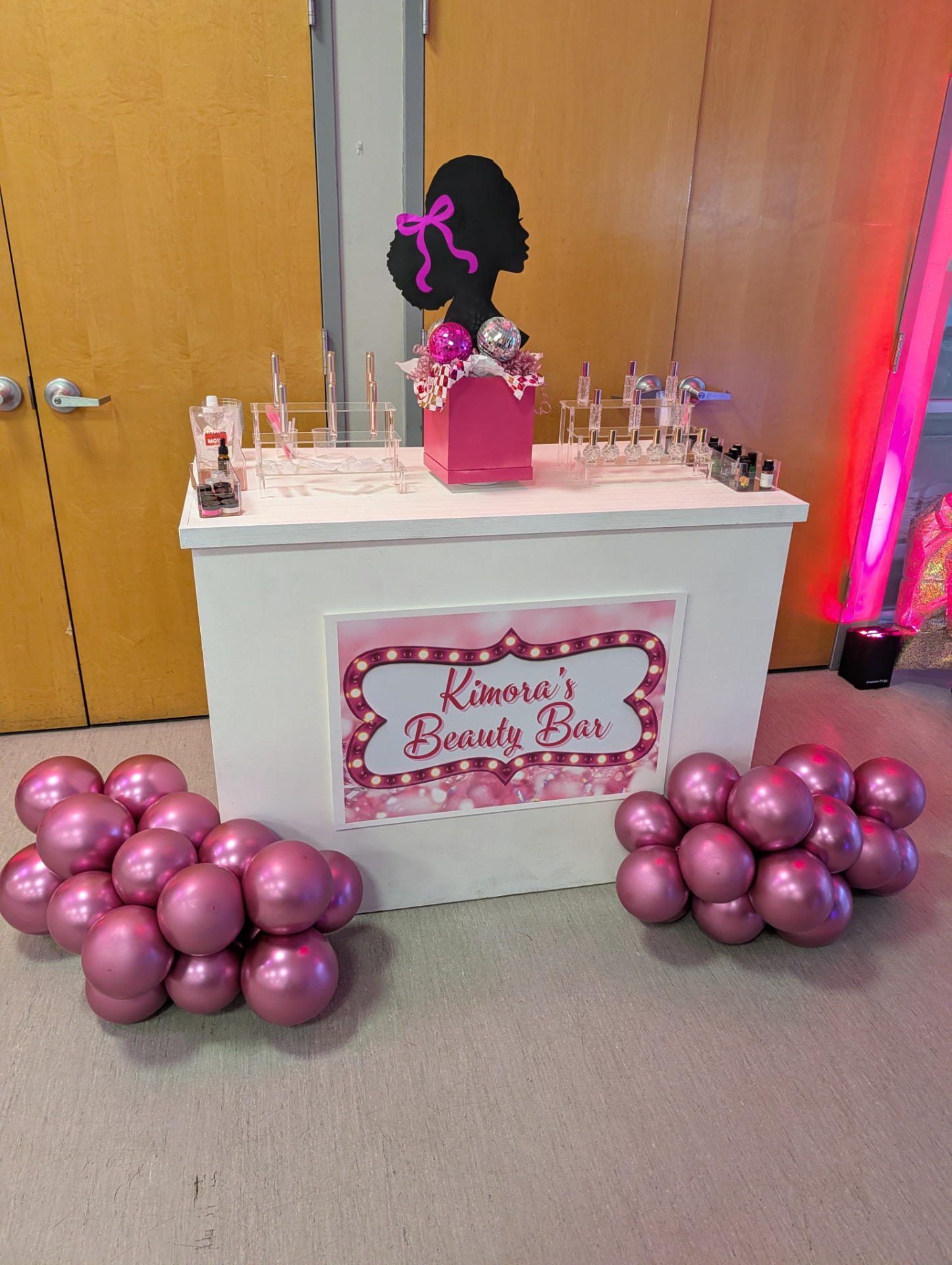 Custom pink Beauty Bar counter with a nail polish display and balloon clusters at the base