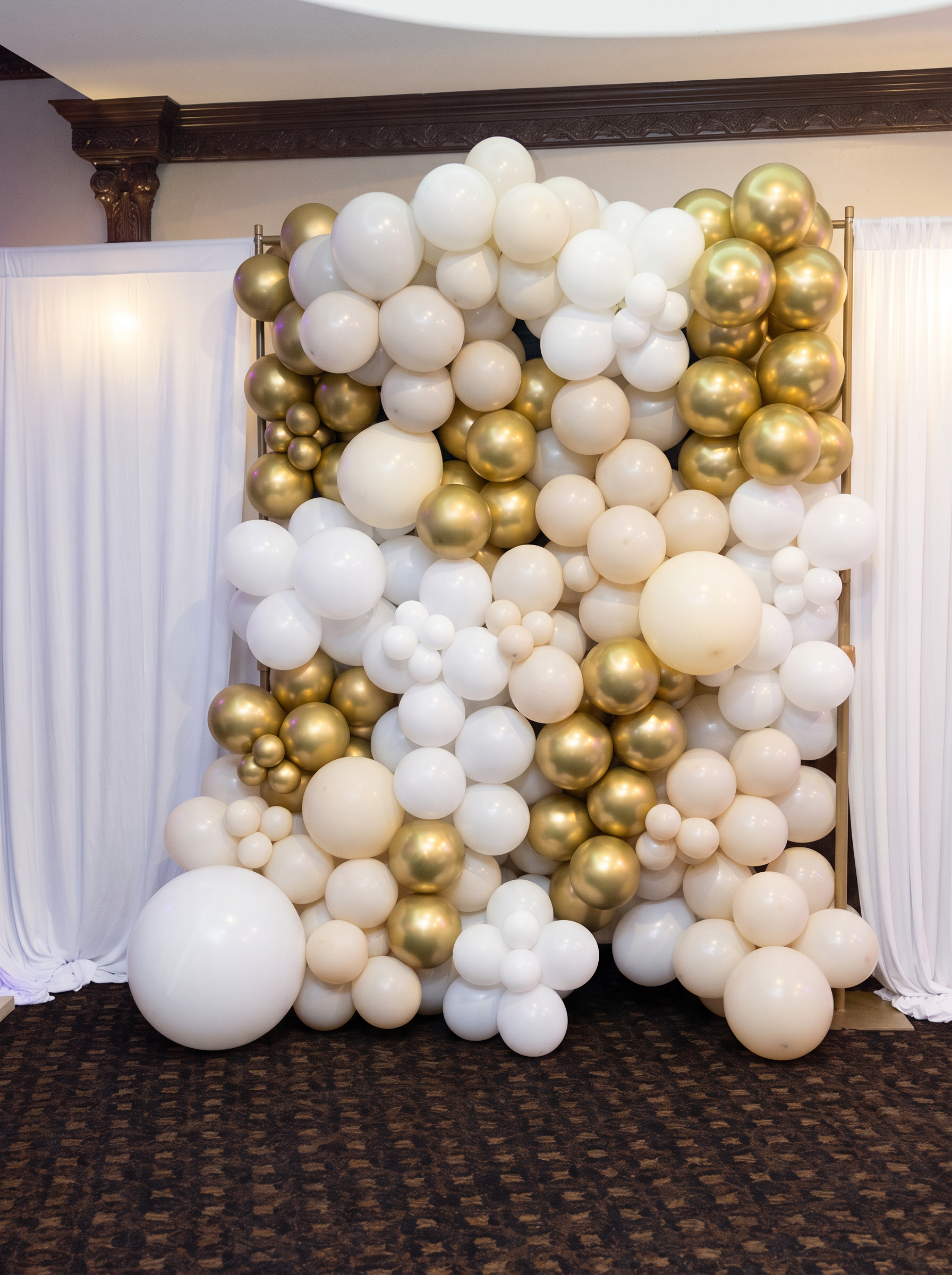 White, ivory and gold chrome organic balloon wall set against white draping