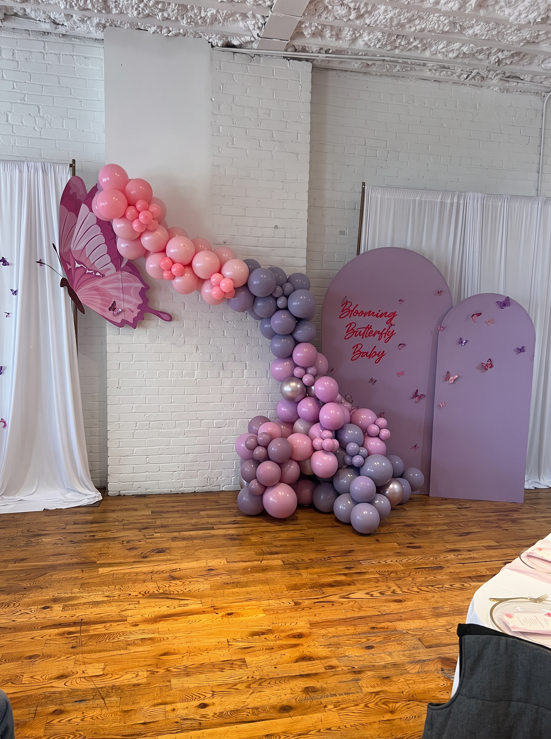 Lavender arched panels with butterfly accents, a pink butterfly wing cutout and a pink and mauve balloon garland