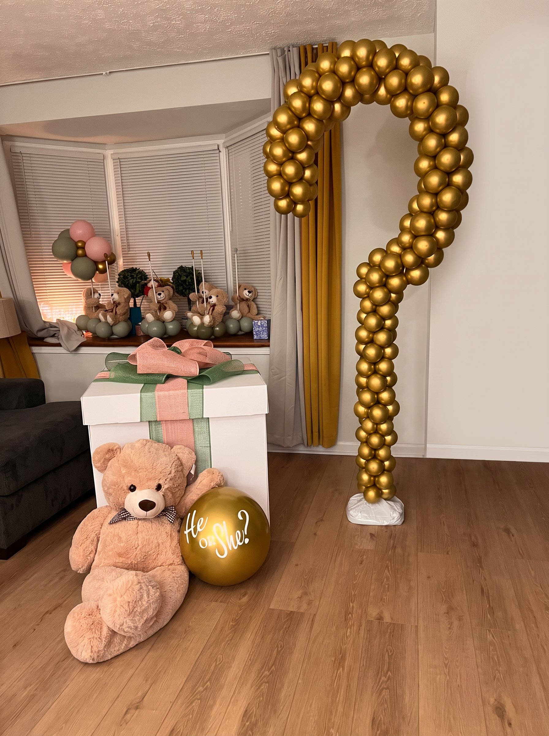 Gold chrome balloon question mark arch with a large reveal gift box, blush and sage bow and teddy bear