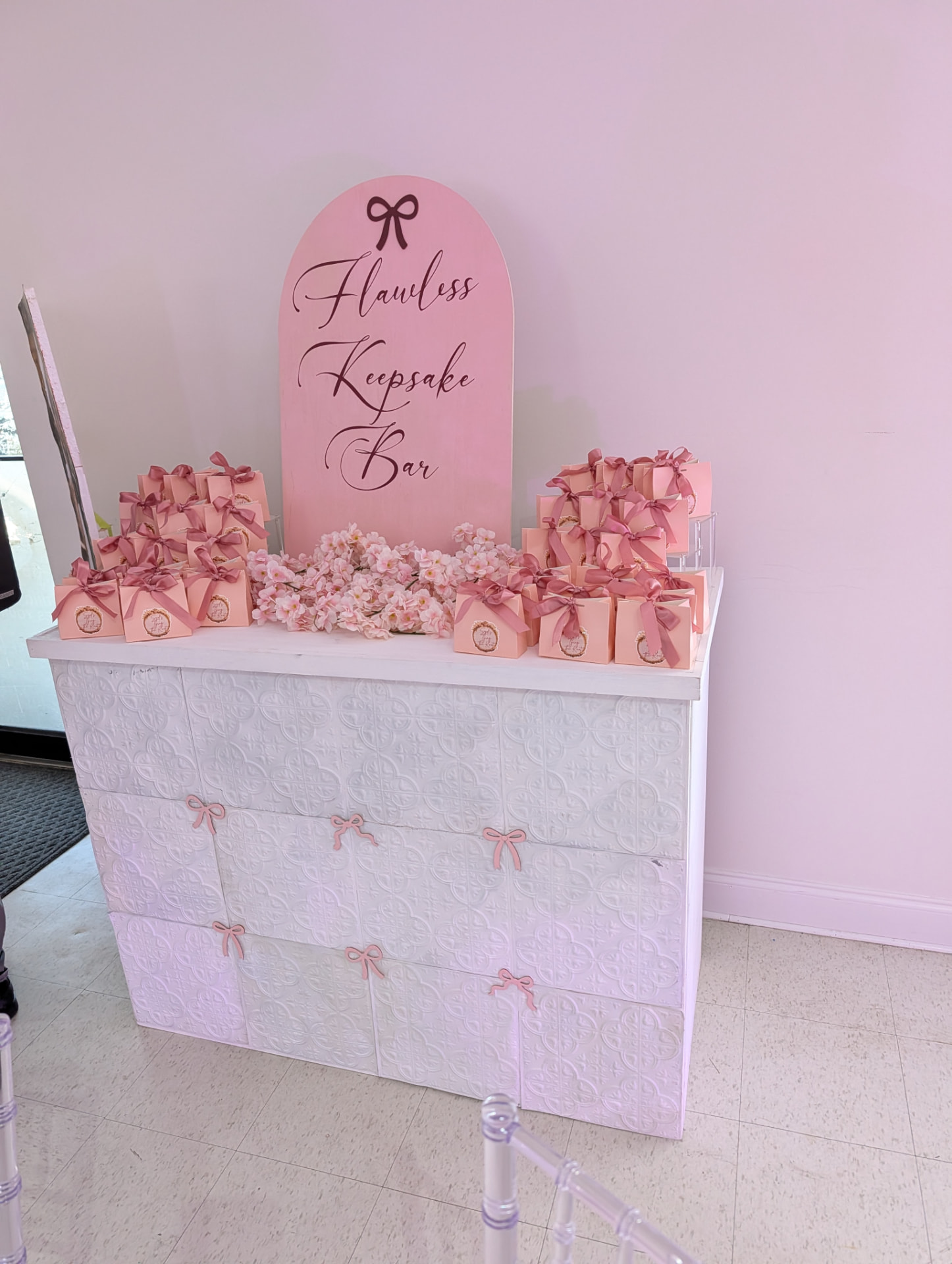 Keepsake bar counter with blush bows, ribboned favor boxes and a pink arched sign